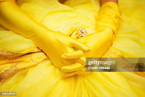 woman's gloved hands laying on dress - yellow glove stock pictures, royalty-free photos & images