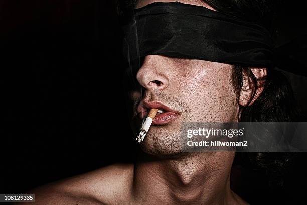 young man wearing blindfold and smoking cigarette - carrying in mouth stock pictures, royalty-free photos & images