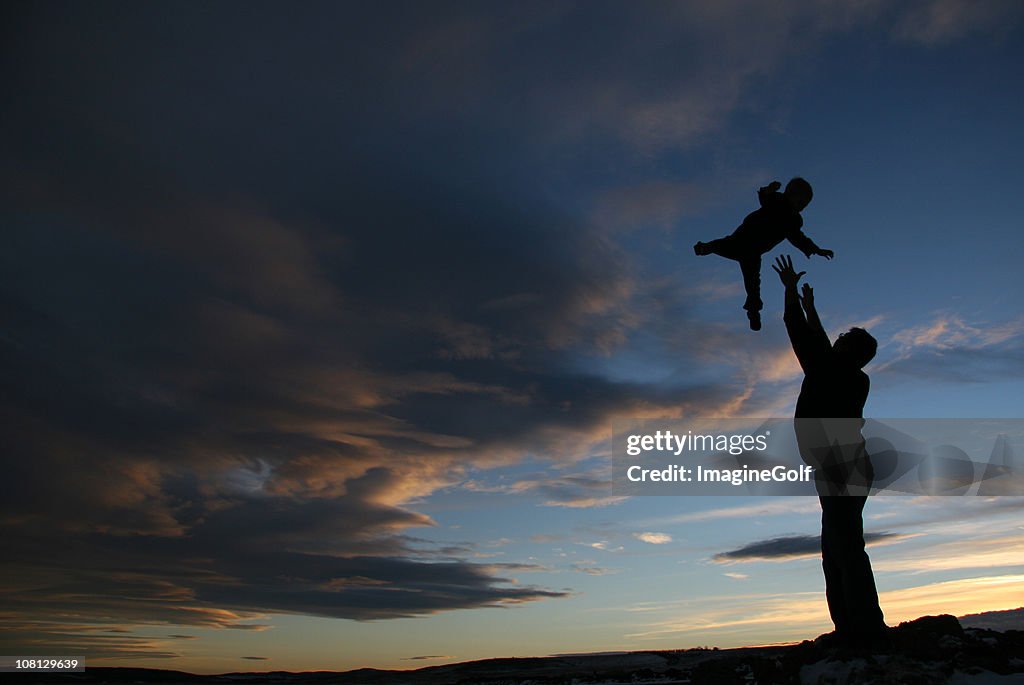 Man throwing kid in air, silhouette