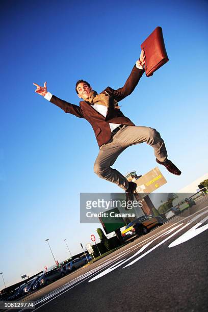 happy businessman jumping in parking lot - tilt up stock pictures, royalty-free photos & images