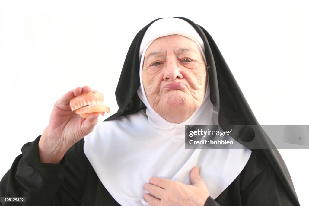 Senior Nun Holding Up Dentures, Isolated on White