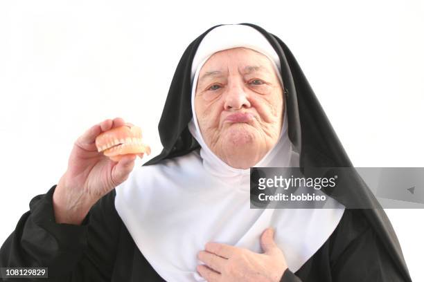 senior nun holding up dentures, isolated on white - nun isolated stock pictures, royalty-free photos & images