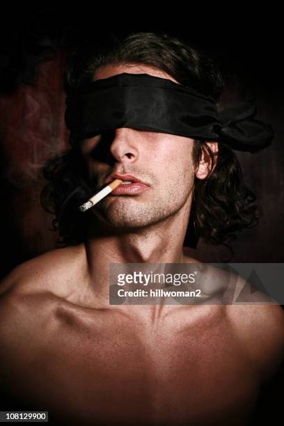 junger mann mit augenbinde und rauchen zigarette - im mund tragen stock-fotos und bilder