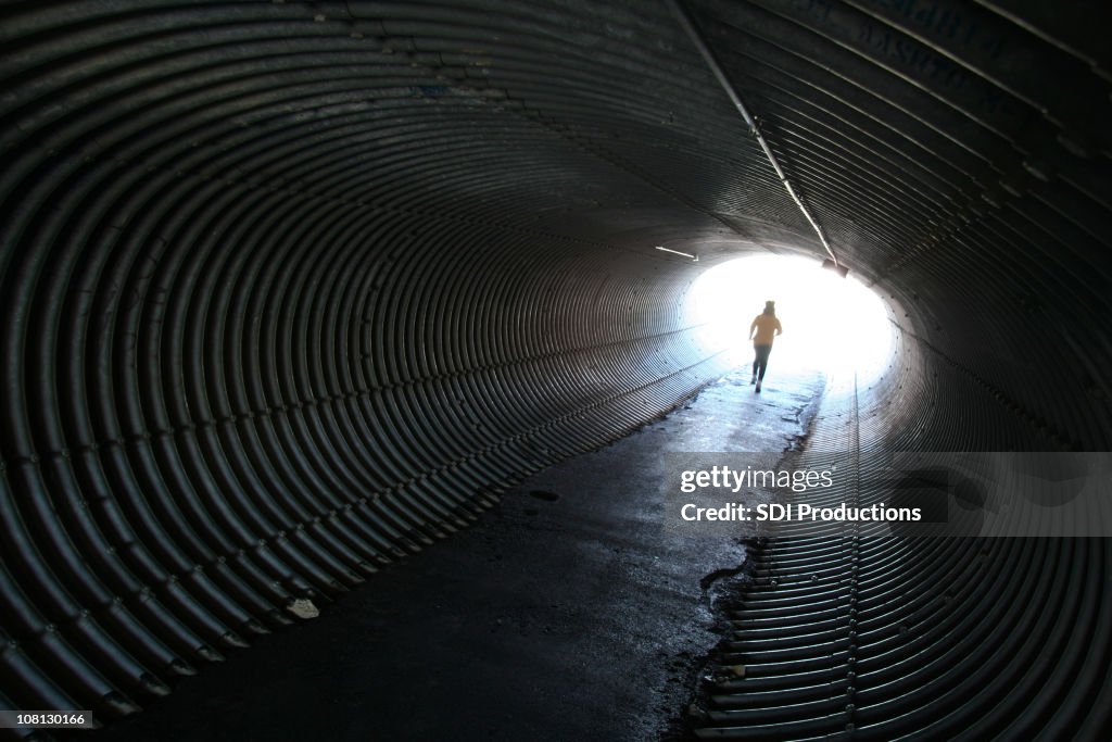 Woman Jogging Through Round Metal Tunnel