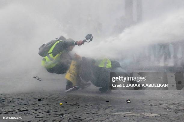 Yellow vests protestors are showered by a water cannon as they clash with police during an anti-government demonstration called by the Yellow Vest...