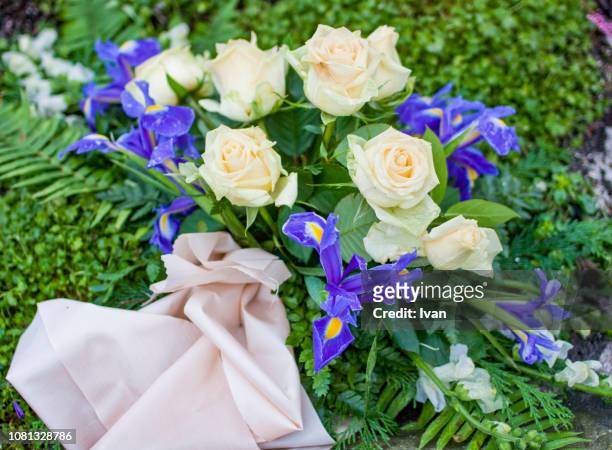 silk flowers on a gravestone, flowers on a cemetery - funeral grief flowers stock-fotos und bilder