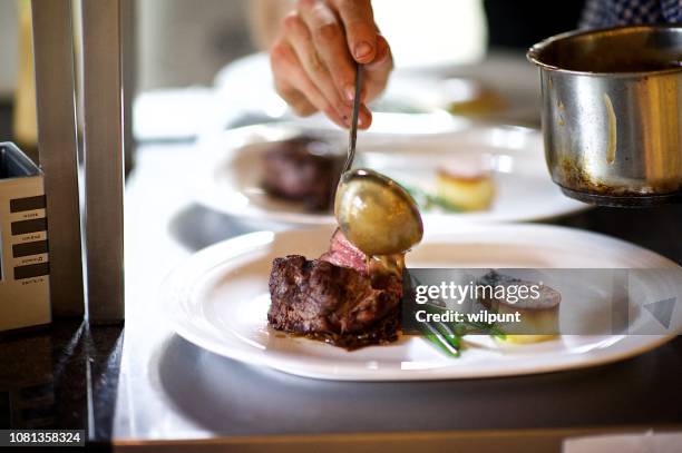 steak op een plaat wordt voorbereid in een chef's keuken saus wordt gegoten - sauce stockfoto's en -beelden