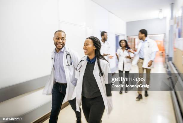 action candid portrait of medical team walking down hospital corridor - junior doctor stock pictures, royalty-free photos & images