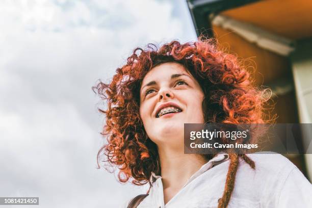 low angle view of woman with redhead standing against cloudy sky - adult retainer ストックフォトと画像