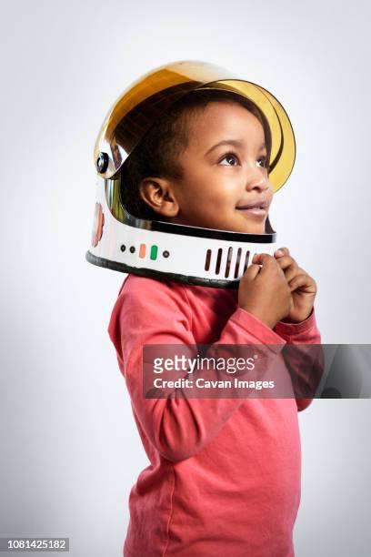 thoughtful girl wearing space helmet while looking away against white background - ruimtehelm stockfoto's en -beelden