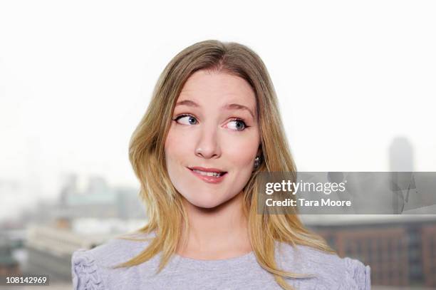 young woman looking uncertain - op de lip bijten stockfoto's en -beelden