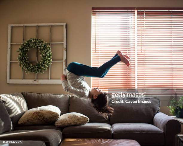 full length of girl backflipping on couch at home - seat perilous stock-fotos und bilder