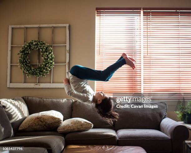 full length of girl backflipping on couch at home - fare le capriole all'indietro foto e immagini stock