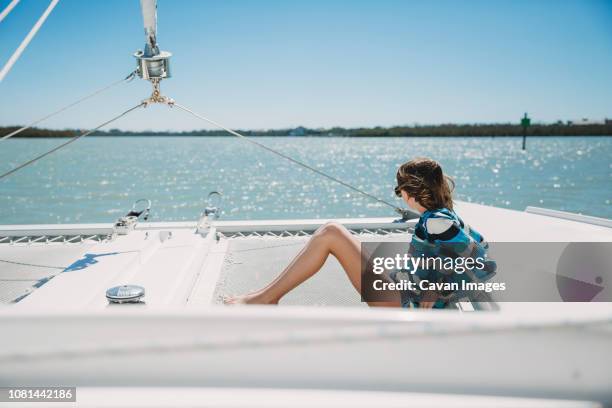 side view of girl sitting in boat on sea against clear sky during sunny day - marco island stock-fotos und bilder