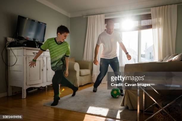 father with son playing soccer at home - football player stock-fotos und bilder