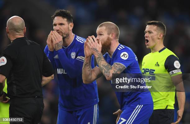 Referee Lee Mason is pursued by Sean Morrison and Aron Gunnarsson as Huddersfield captain Jonathan Hogg reacts after Mason had awarded a penalty to...