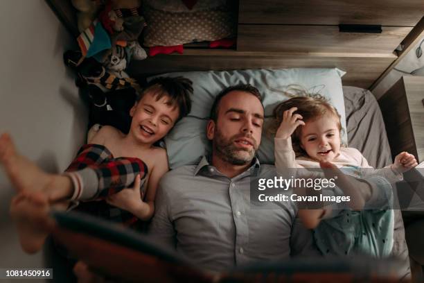 high angle view of father reading book for children while lying on bed at home - boa noite imagens e fotografias de stock