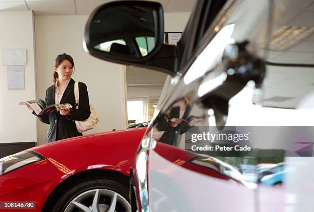 chinese female executive in car showroom - comprar coche fotografías e imágenes de stock