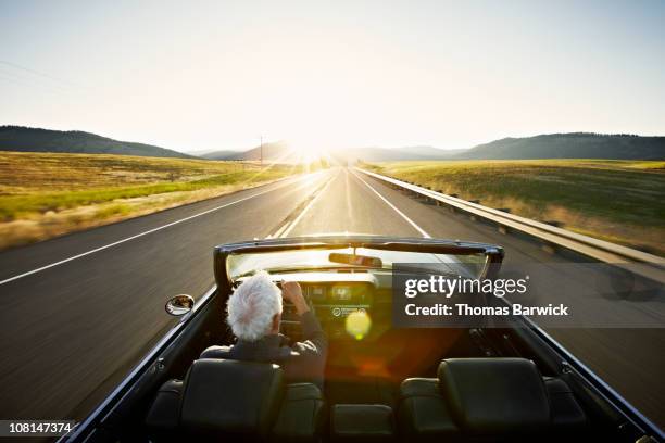 senior man driving convertible car at sunrise - on the move rear view stockfoto's en -beelden