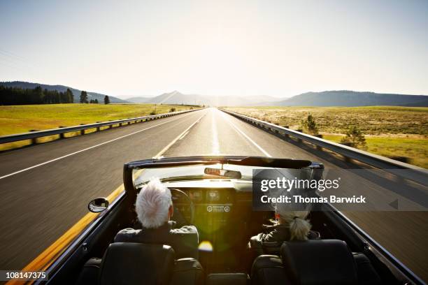 senior couple driving convertible car at sunrise - ländliche straße stock-fotos und bilder