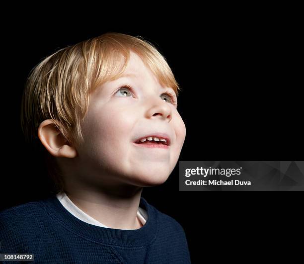 studio portrait of young boy on a black background - black boy ストックフォトと画像