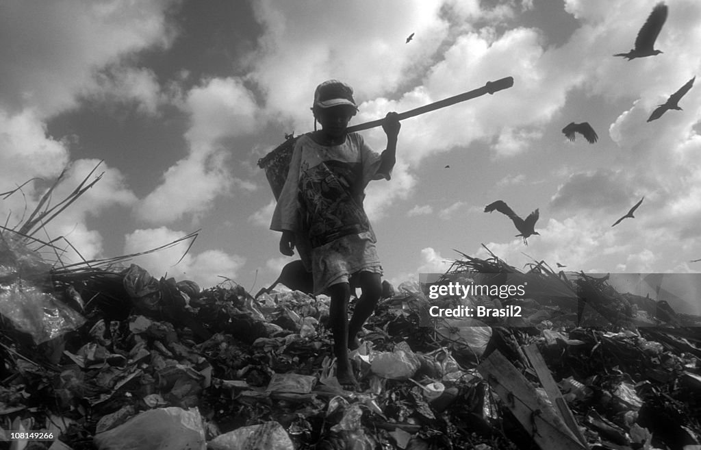 Young Boy Climbing and Picking Through Landfill
