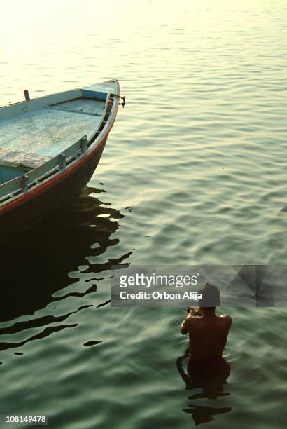 young man standing in ganga river near boat - wade stock pictures, royalty-free photos & images