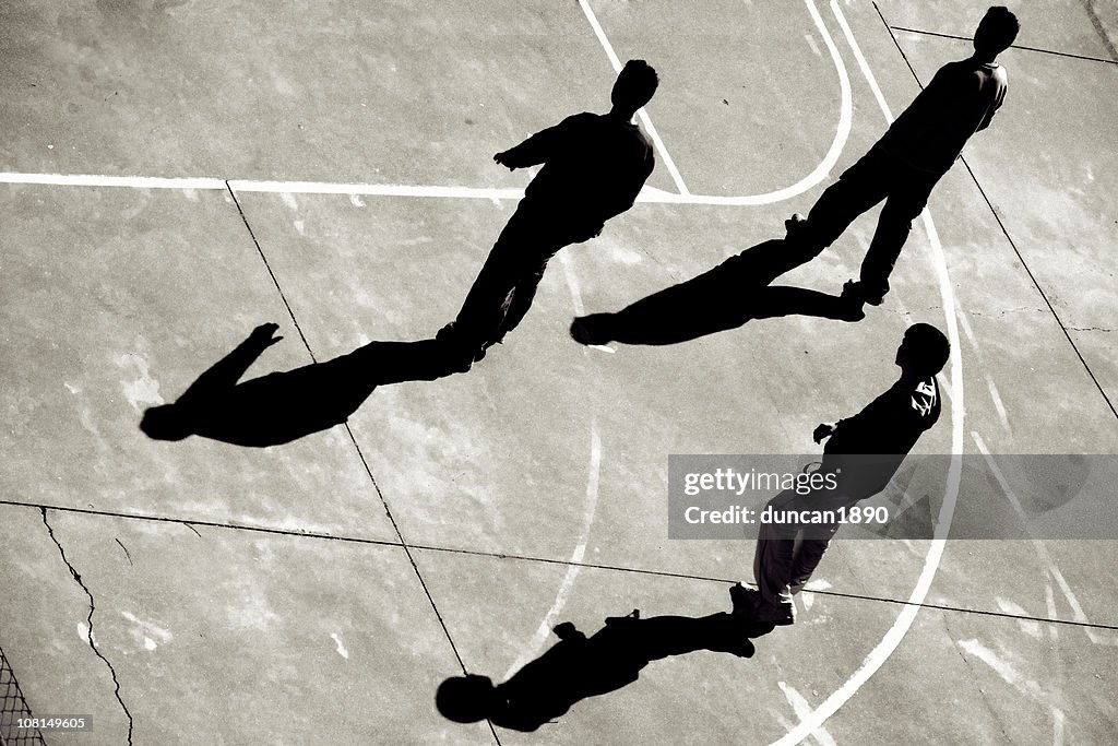 Três Meninos Adolescentes a caminhar no campo de basquetebol