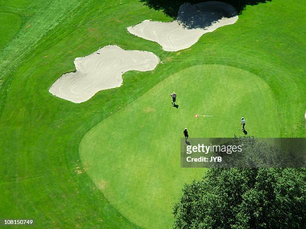 aerial view of players on a green golf course - golf course stock pictures, royalty-free photos & images
