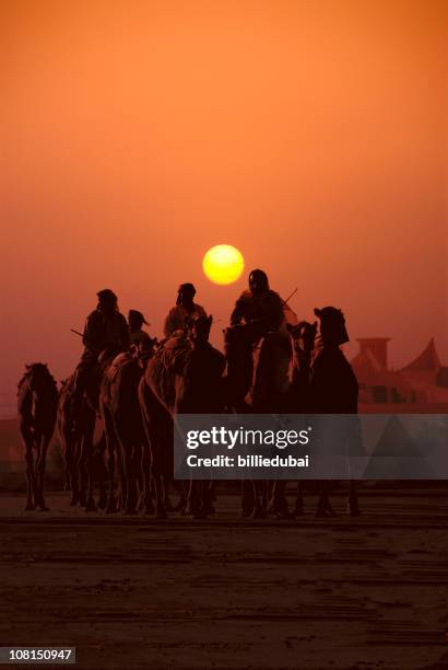 caravan of people travelling on camels at sunset - riding camel stock pictures, royalty-free photos & images