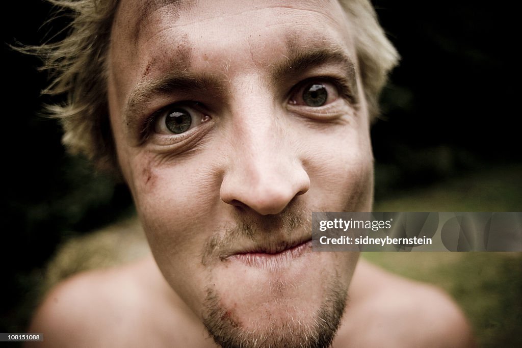 Verrückte junge Mann überdachte in Schmutz und Prellungen außerhalb