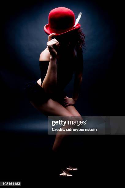 young woman tipping red bowler hat, low key - cabaret stock pictures, royalty-free photos & images