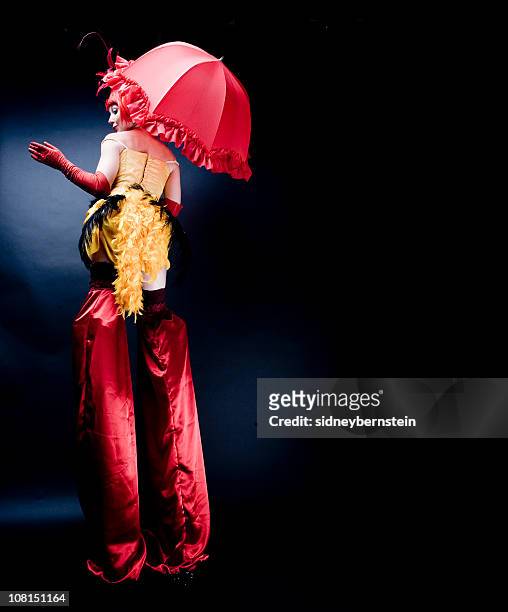 circus performer in costume wearing stilts, low key - styltor bildbanksfoton och bilder