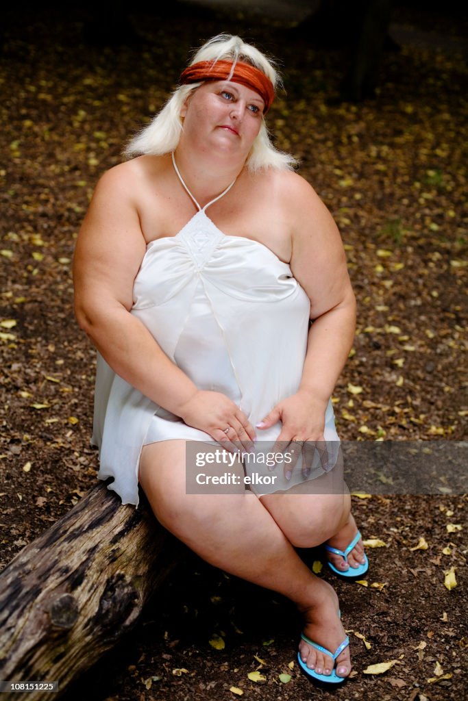 Portrait of Overweight Woman Sitting on Log in Forest