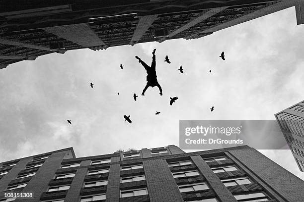 businessman falling off office building roof with birds flying - falling stock pictures, royalty-free photos & images
