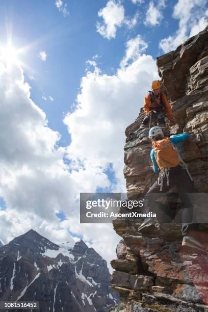 climber gives a helping hand to other climber - clambering imagens e fotografias de stock