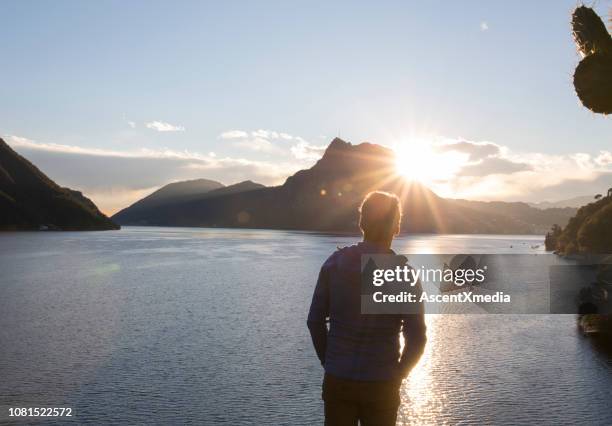 view past man to lake, sun and mountains - winter still life stock pictures, royalty-free photos & images