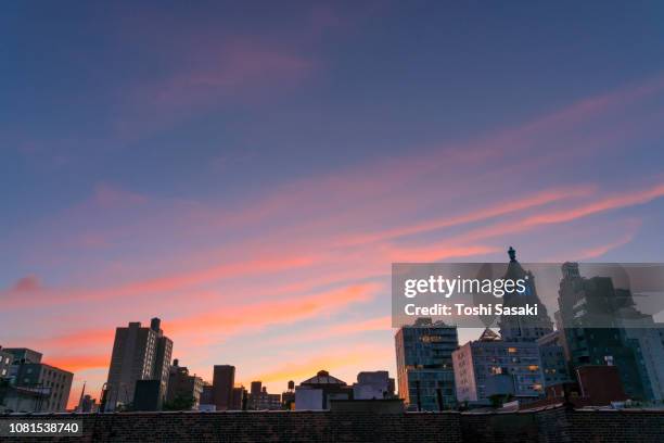 clouds are glowing red and cover the east village cityscape during the sunset at new york ny usa on jun. 25 2018. - east village stock pictures, royalty-free photos & images