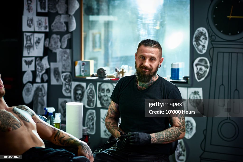 Portrait of male tattoo artist in tattoo parlour facing camera