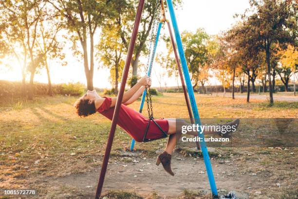 junge frau auf einer schaukel in einem park - schaukel frau stock-fotos und bilder
