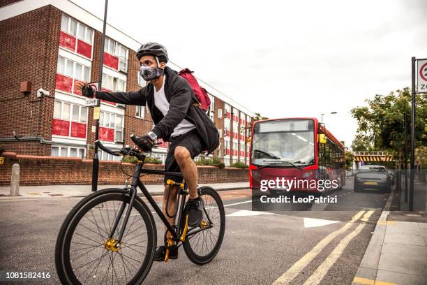 fietser commuter dragen van een verontreiniging-masker in centraal londen - london buses stockfoto's en -beelden