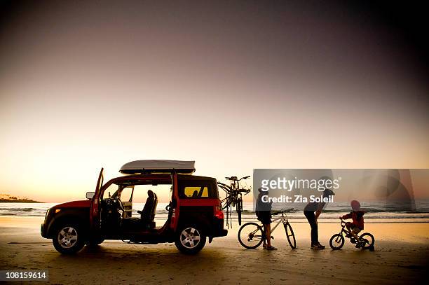 family on beach with bikes and car, sunset - bike beach stockfoto's en -beelden