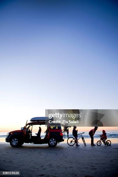 family on beach with car and bikes, sunset - us girls on the beach stock-fotos und bilder