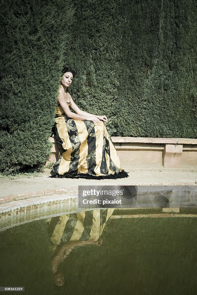 Woman Sitting on Edge of Garden Pond