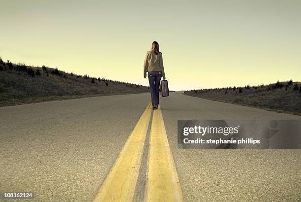 lonely woman walking down the road with her luggage - runaway stock pictures, royalty-free photos & images