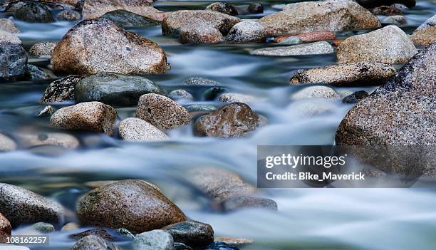 close-up of clear water flowing through pebbles in stream - rocks stockfoto's en -beelden