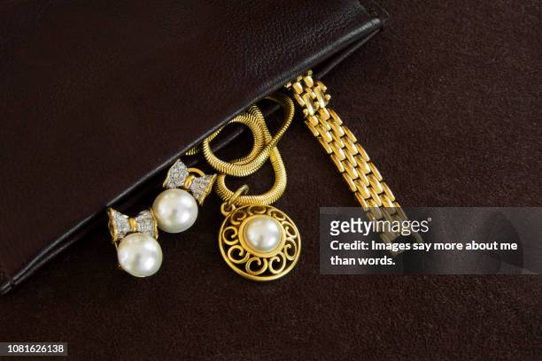 an open leather bag showing some golden jewlery. still life. close eup. - earring stock-fotos und bilder