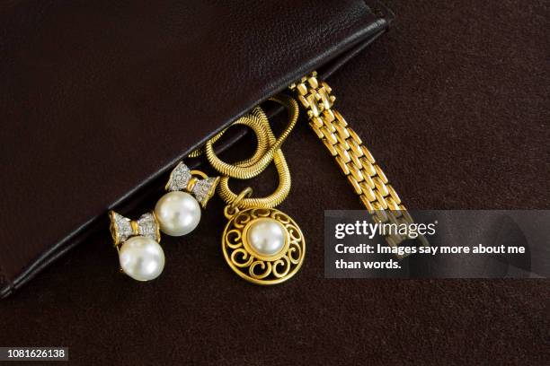 an open leather bag showing some golden jewlery. still life. close eup. - gold purse stockfoto's en -beelden