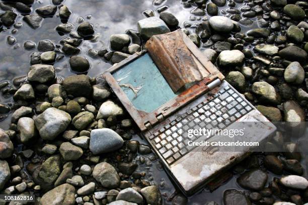 abandoned and rusted laptop lying on riverbed - e waste stock pictures, royalty-free photos & images