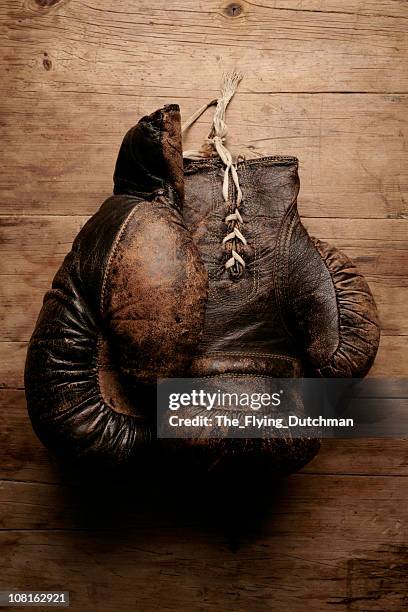 a pair of worn old boxing gloves on wooden table - durability stock pictures, royalty-free photos & images